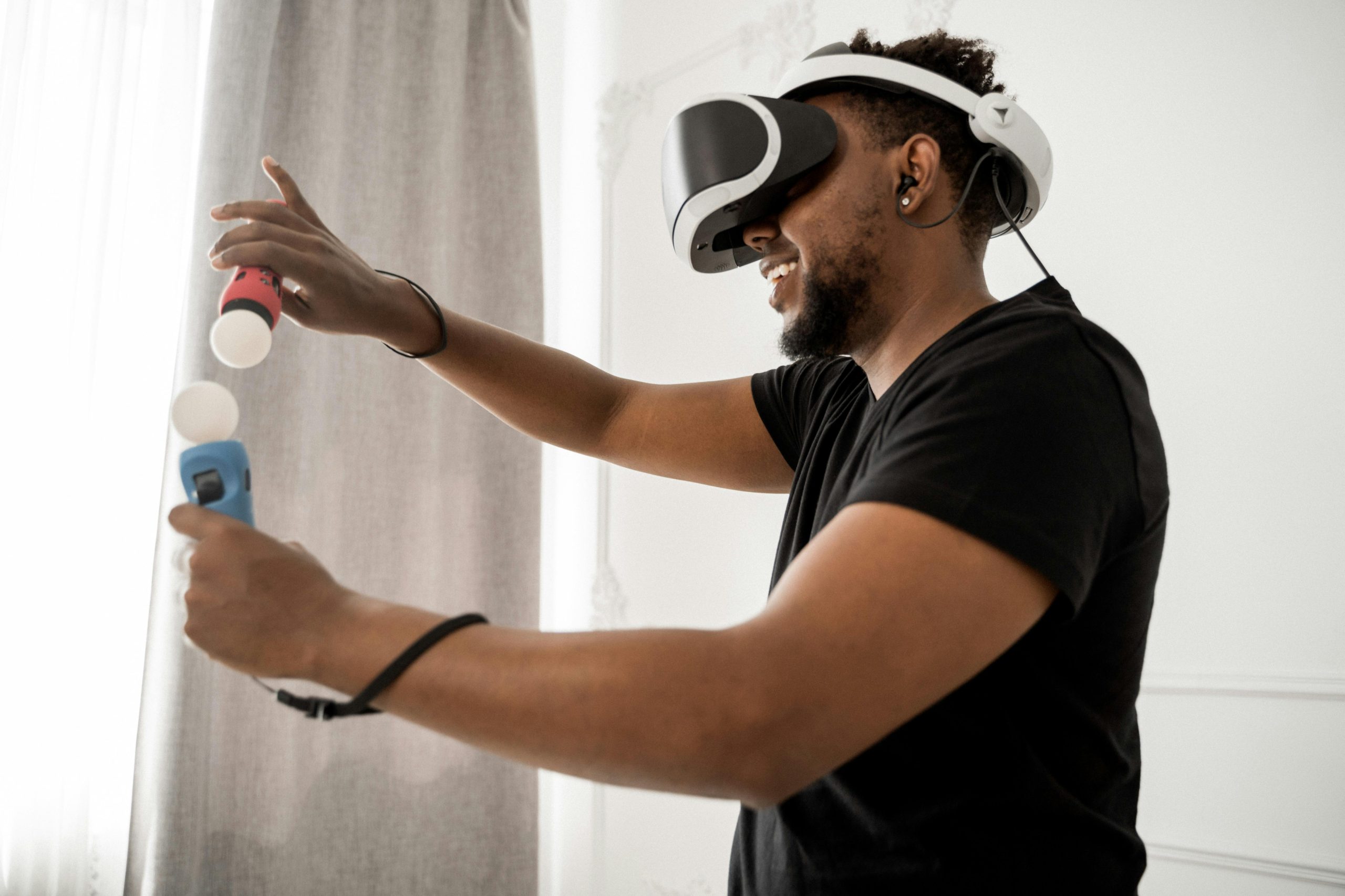 An adult man participates in a virtual reality simulation using VR glasses and controllers indoors.